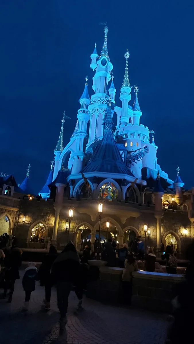 Sleeping Beauty Castle lit blue at Disneyland Paris at night